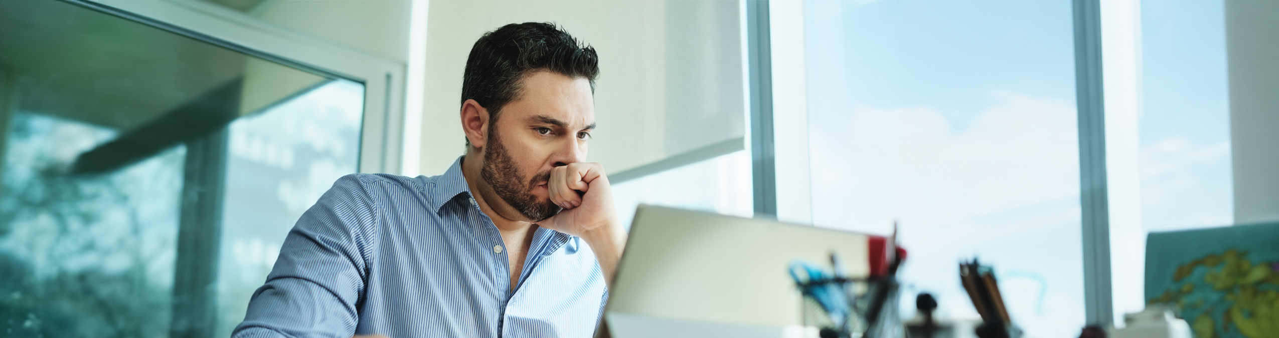 Worried man sitting in his office staring at a computer
