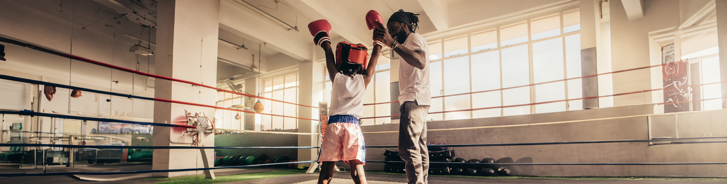 Boxing Coach holding up the hand of a boxing student
